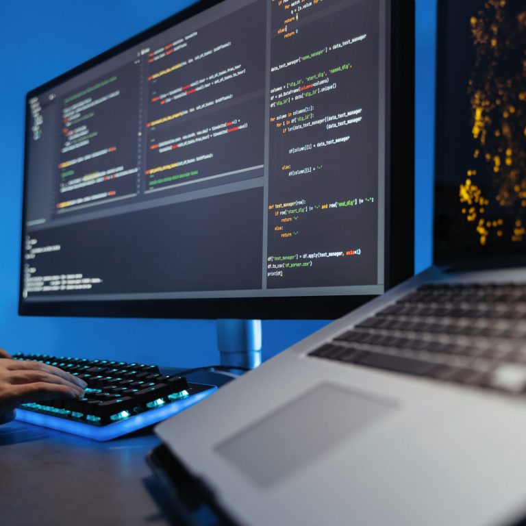 Data science concept. No face image of male hands typing on keyboard, writing html code for website, sitting at desk with pc and laptop, working on project in software development company
